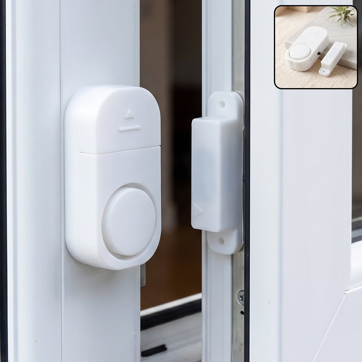 A white magnetic door and window security alarm is installed on a white window frame, with the two pieces separated.